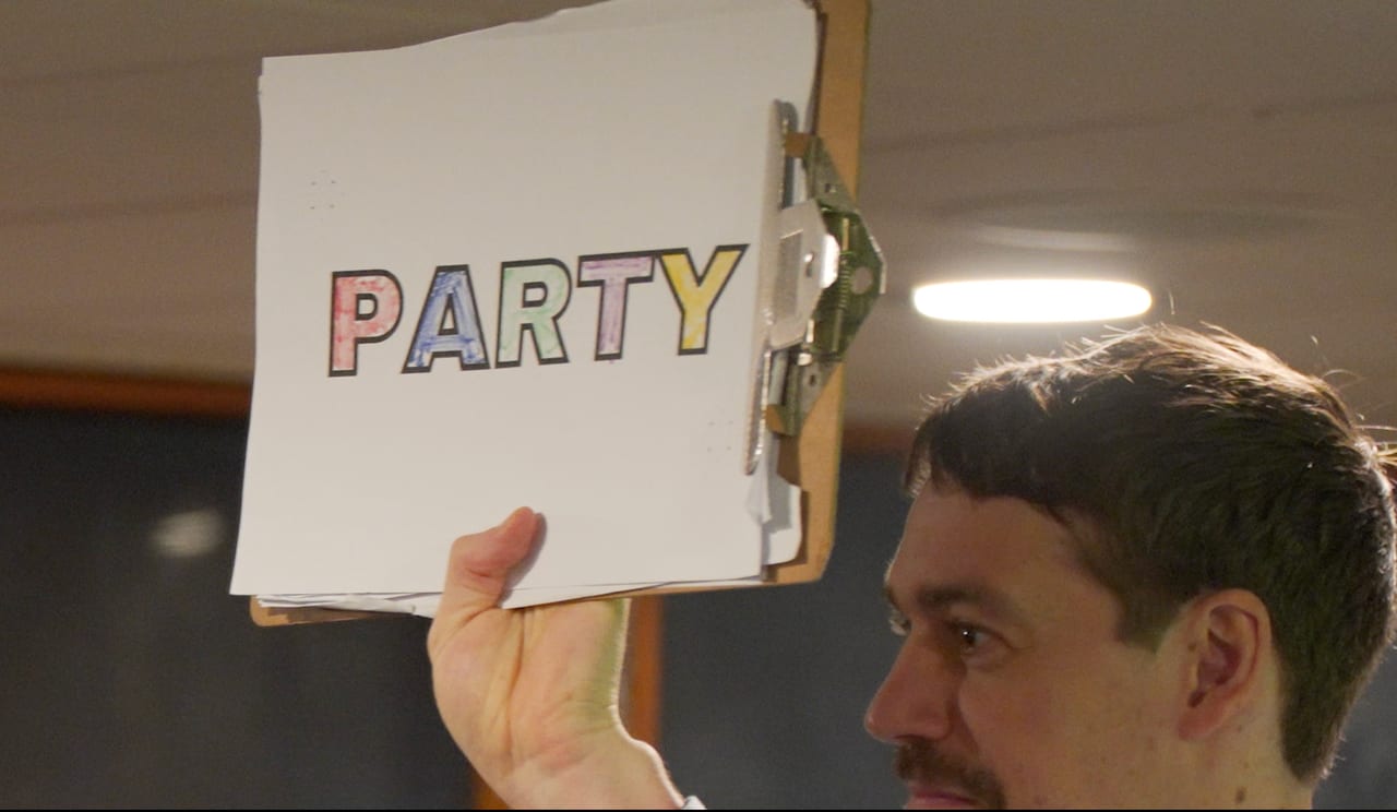 A Viva Funcouver host holding up a colourful PARTY sign